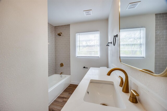 bathroom featuring hardwood / wood-style floors, tiled shower / bath combo, and vanity