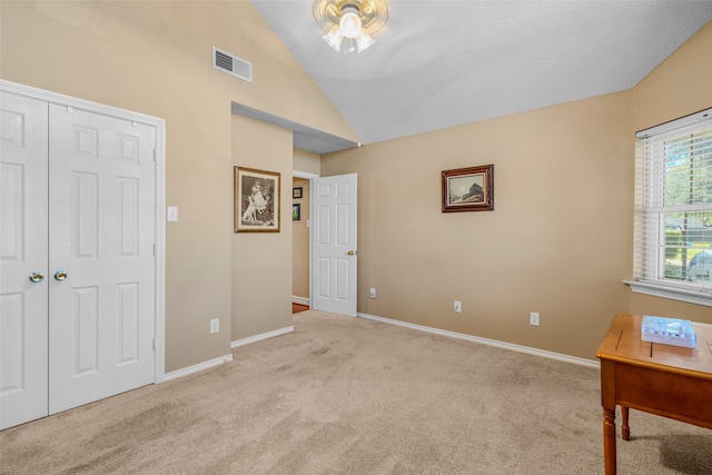 unfurnished bedroom featuring light colored carpet, a closet, and lofted ceiling