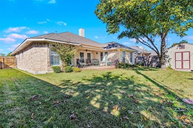 back of house featuring a lawn, a storage unit, ceiling fan, and a patio