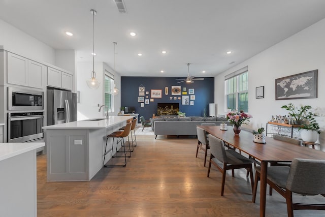 kitchen featuring a center island with sink, a kitchen bar, white cabinets, appliances with stainless steel finishes, and sink