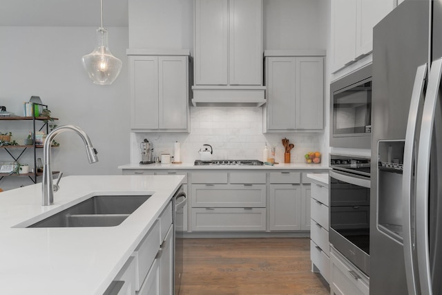 kitchen with stainless steel appliances, dark hardwood / wood-style flooring, pendant lighting, sink, and backsplash