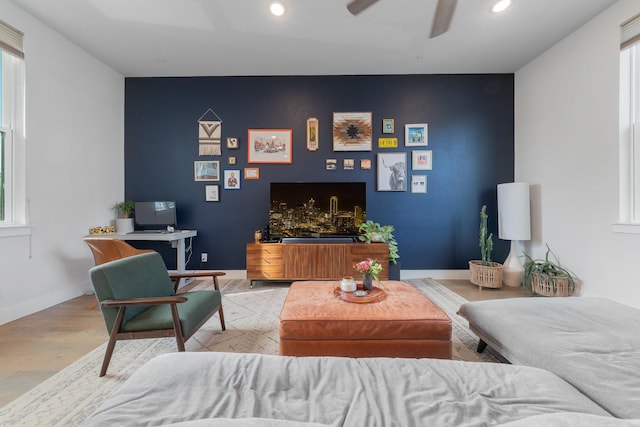 living room featuring an accent wall, baseboards, wood finished floors, and recessed lighting