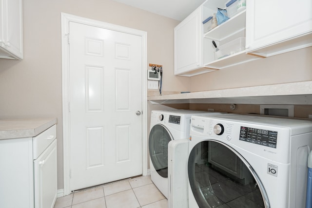 laundry area featuring light tile patterned flooring, cabinets, and washing machine and dryer