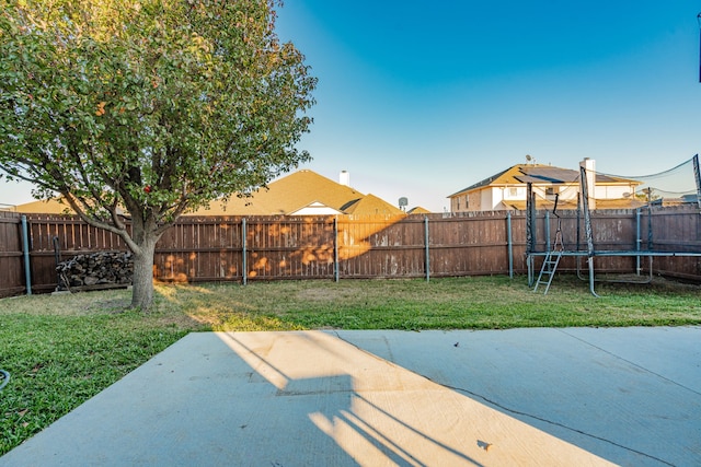 view of yard with a trampoline and a patio area