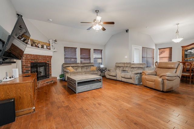 living room with ceiling fan, plenty of natural light, light hardwood / wood-style floors, vaulted ceiling, and a fireplace