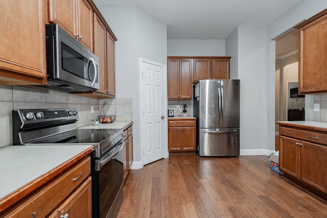 kitchen with dark hardwood / wood-style flooring, stainless steel appliances, and tasteful backsplash