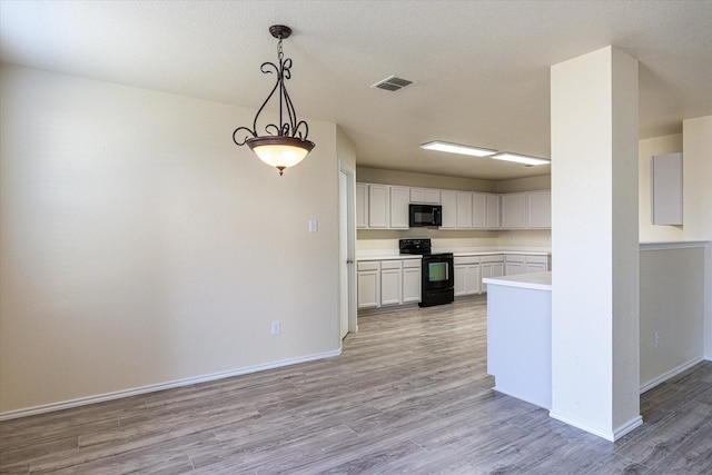 kitchen with light hardwood / wood-style flooring, white cabinets, black appliances, and decorative light fixtures