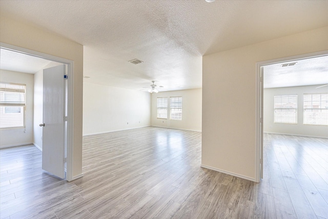 empty room featuring ceiling fan, a textured ceiling, and light wood-type flooring