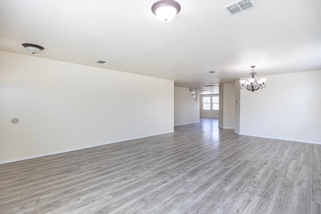 spare room featuring a chandelier and light wood-type flooring