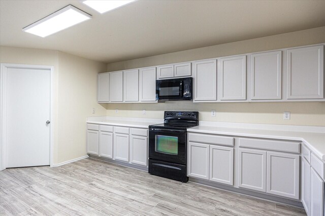 kitchen with white cabinets, light wood-type flooring, and black appliances