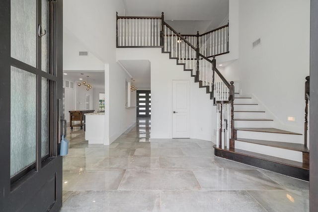 entryway featuring a towering ceiling and an inviting chandelier