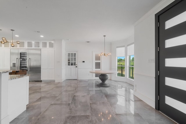 foyer entrance featuring crown molding and a notable chandelier