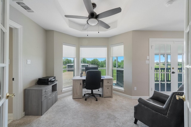 home office with light colored carpet, a raised ceiling, ceiling fan, and plenty of natural light