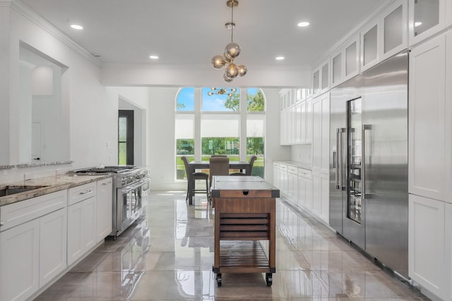 kitchen with white cabinets, premium appliances, decorative light fixtures, and light stone countertops