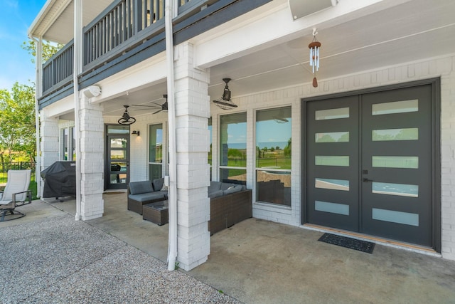 entrance to property with french doors, a balcony, an outdoor living space, ceiling fan, and a patio area