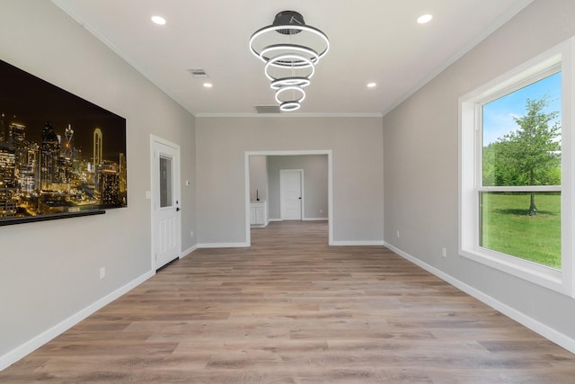 unfurnished dining area with light hardwood / wood-style floors, an inviting chandelier, a wealth of natural light, and ornamental molding