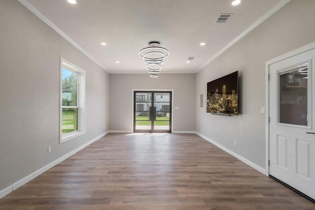 unfurnished room with hardwood / wood-style floors, crown molding, and a wealth of natural light