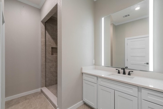 bathroom featuring a tile shower, vanity, and ornamental molding