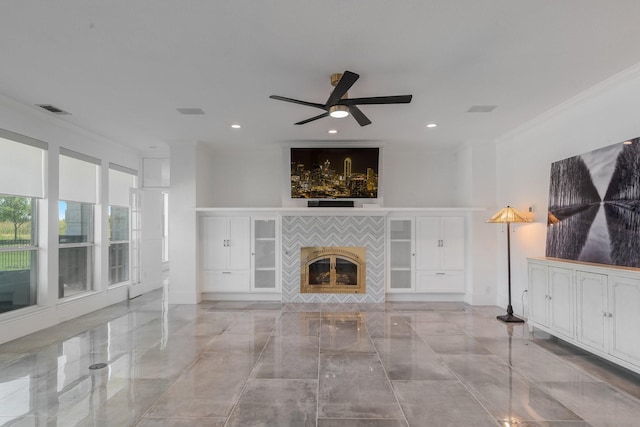 unfurnished living room featuring a tiled fireplace, ceiling fan, and ornamental molding