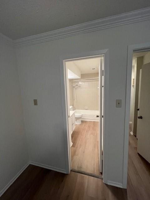 hallway with ornamental molding and dark wood-type flooring