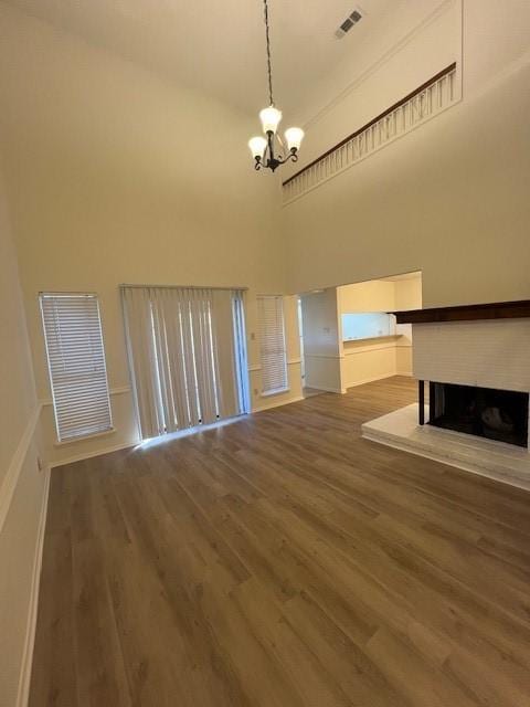 unfurnished living room with a high ceiling, an inviting chandelier, and wood-type flooring