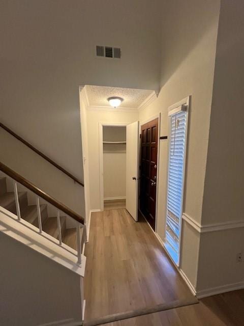 entryway with wood-type flooring and ornamental molding