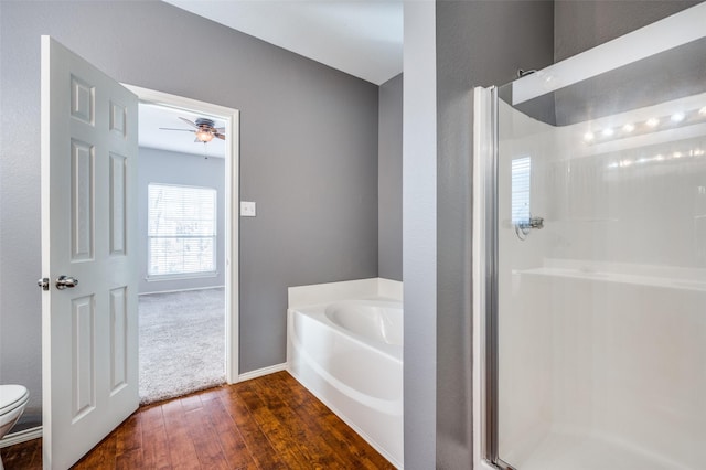 bathroom featuring plus walk in shower, wood-type flooring, toilet, and ceiling fan