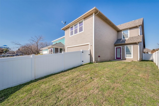 rear view of house with a garage and a yard