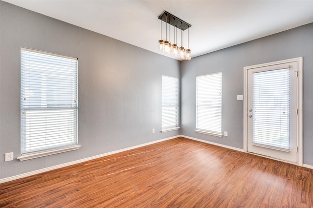 unfurnished room with a chandelier and wood-type flooring