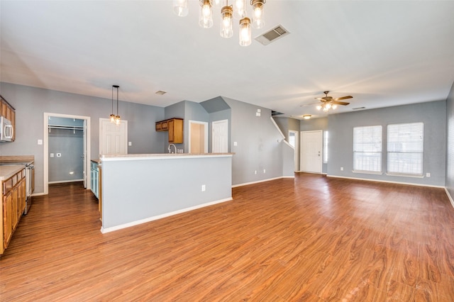 unfurnished living room featuring wood-type flooring, ceiling fan, and sink