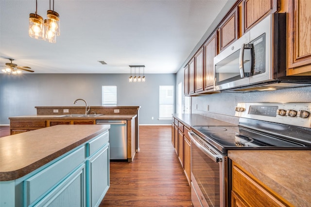 kitchen featuring sink, ceiling fan, decorative light fixtures, a kitchen island, and stainless steel appliances