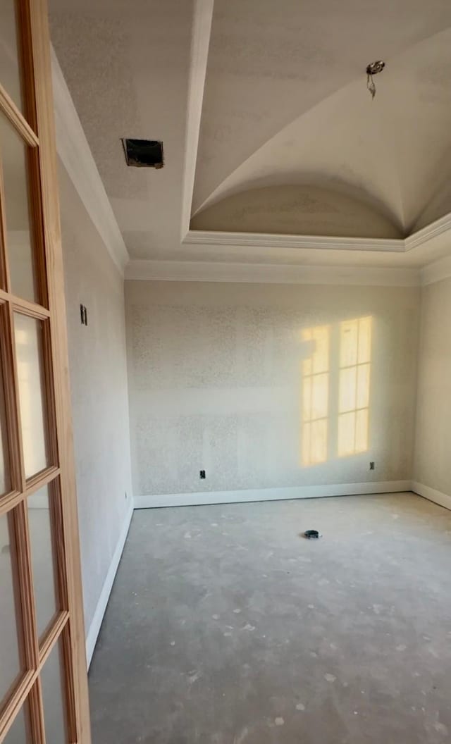 unfurnished room with concrete floors, vaulted ceiling, and ornamental molding