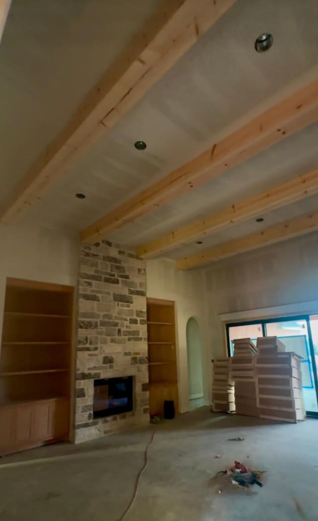 unfurnished living room with beamed ceiling and a fireplace