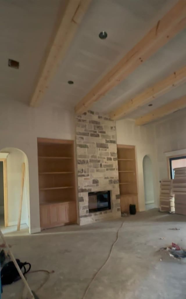 unfurnished living room with beam ceiling and a large fireplace