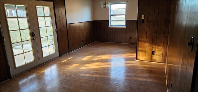 spare room featuring a chandelier, hardwood / wood-style flooring, and wood walls