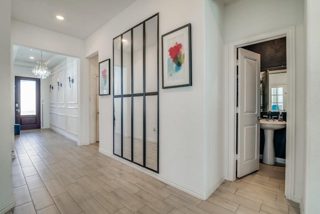 corridor featuring crown molding, light hardwood / wood-style flooring, a chandelier, and sink