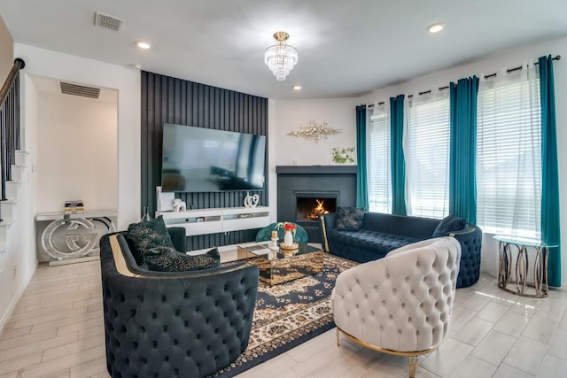 living room with a tiled fireplace, light hardwood / wood-style floors, and a notable chandelier