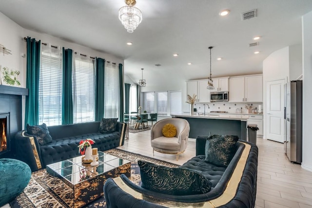 living room with a chandelier, light wood-type flooring, and sink