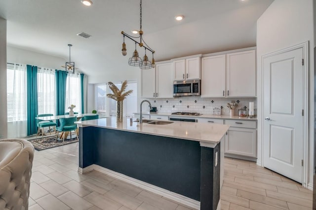 kitchen featuring decorative light fixtures, stainless steel appliances, white cabinetry, and sink