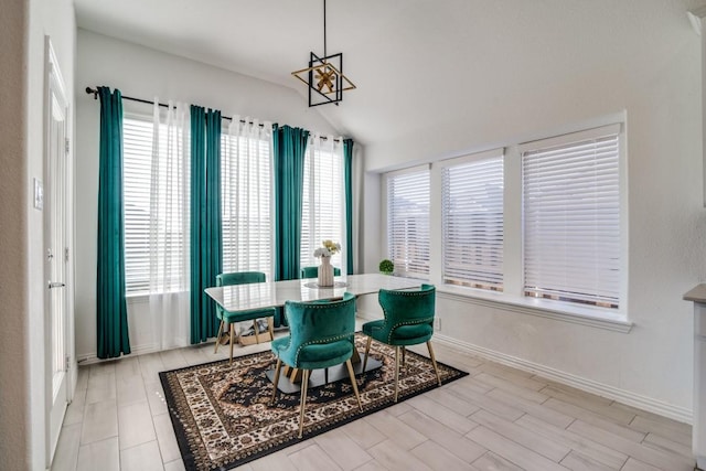 dining room with light hardwood / wood-style floors, lofted ceiling, and a notable chandelier