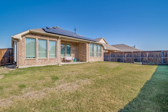 rear view of property with a lawn and solar panels