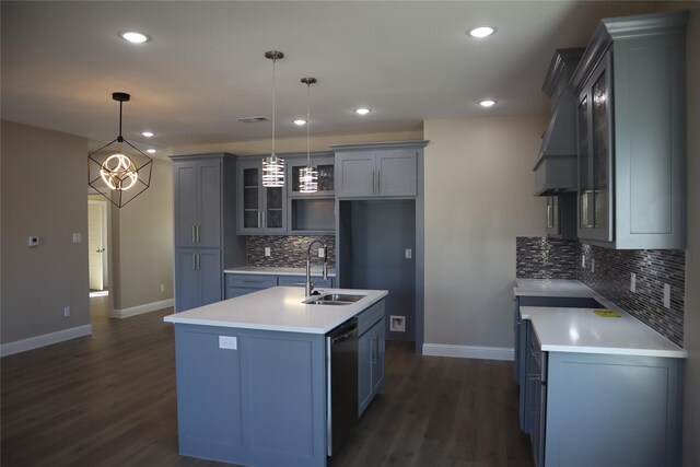 kitchen featuring pendant lighting, dark hardwood / wood-style floors, stainless steel dishwasher, and a kitchen island with sink