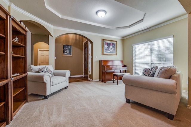 sitting room with light carpet, a tray ceiling, and ornamental molding