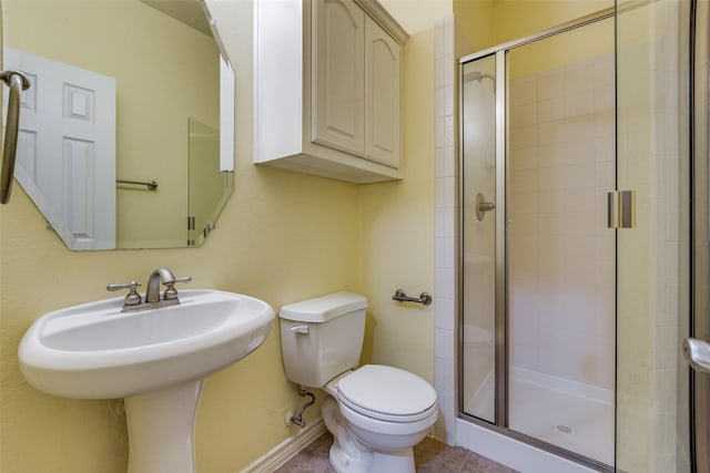 bathroom with tile patterned floors, toilet, a shower with door, and sink