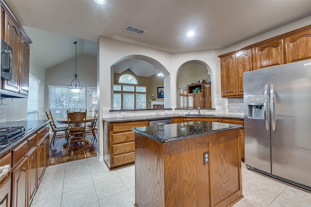 kitchen featuring decorative backsplash, appliances with stainless steel finishes, sink, dark stone countertops, and a kitchen island