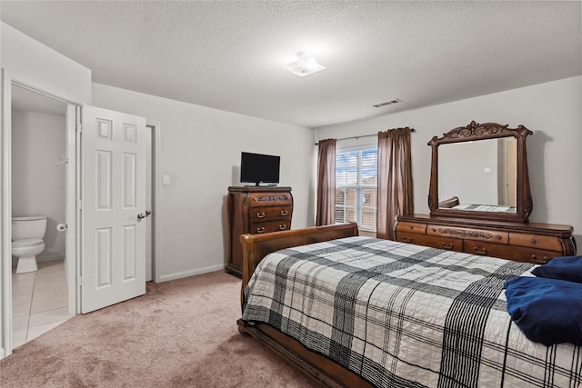 bedroom featuring ensuite bath, light colored carpet, and a textured ceiling