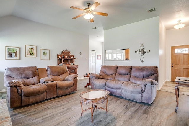 living room with a wealth of natural light, ceiling fan, wood-type flooring, and vaulted ceiling