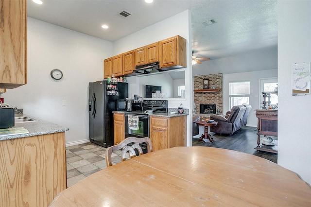 kitchen with ceiling fan, sink, black appliances, light hardwood / wood-style flooring, and a fireplace