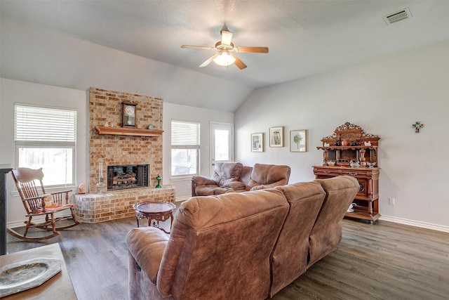 living room featuring a brick fireplace, dark hardwood / wood-style floors, vaulted ceiling, and ceiling fan