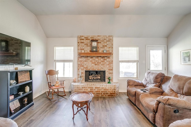 living room featuring wood-type flooring, lofted ceiling, ceiling fan, and a fireplace